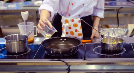 Person cooking food over a stove 